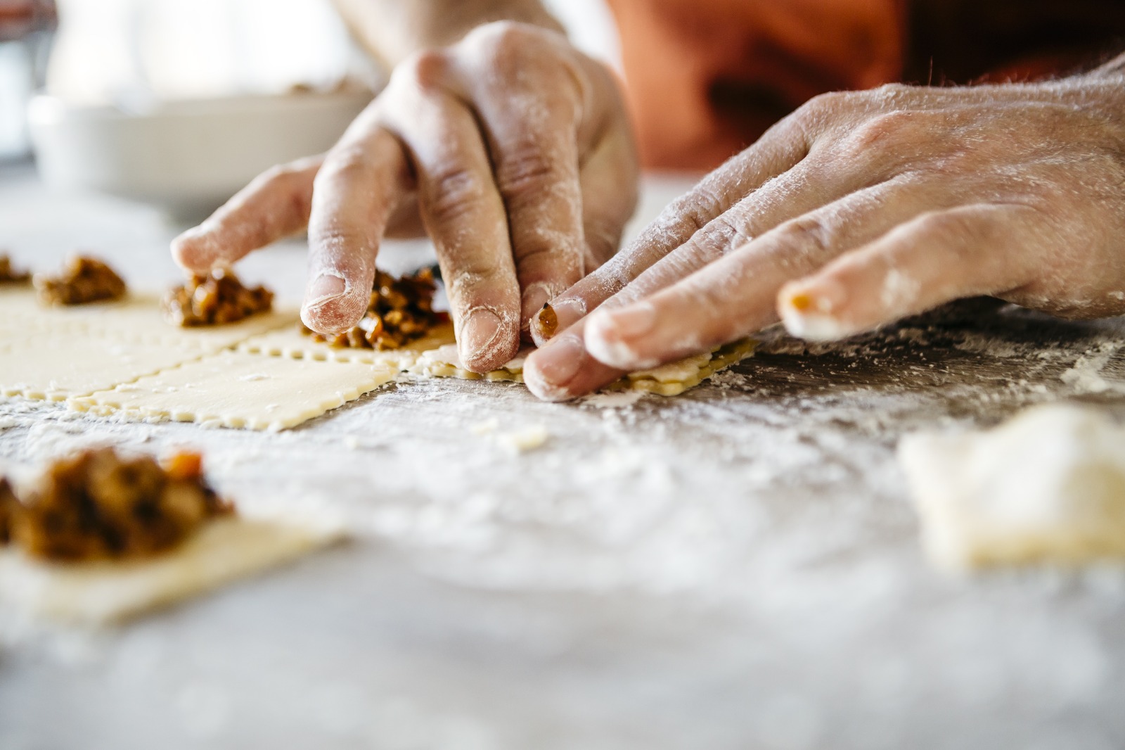 Manos amasando masa rellena sobre superficie enharinada